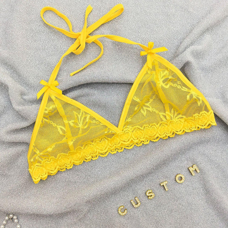 Yellow lace bralette with floral mesh, adjustable tie straps, and scalloped trim on gray fabric