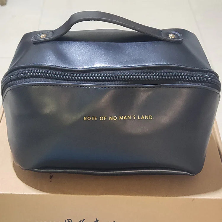 Black faux leather zippered clutch bag with top handle and gold text, rectangular shape
