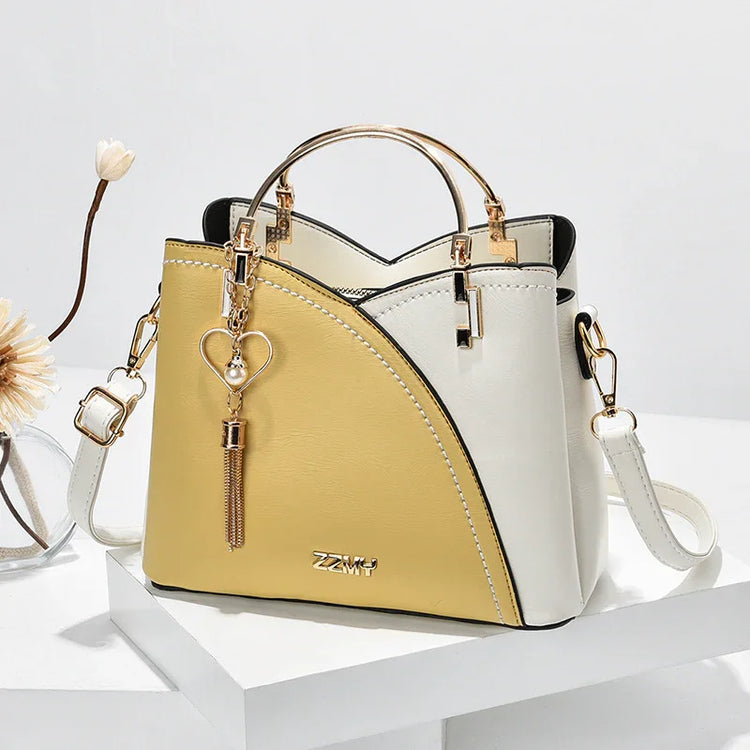 Two-tone yellow and white faux leather handbag with gold hardware, structured fit, and heart charm.
