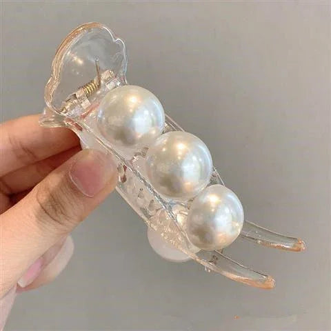 Clear acrylic hair claw clip with three large glossy pearl accents, hand holding accessory