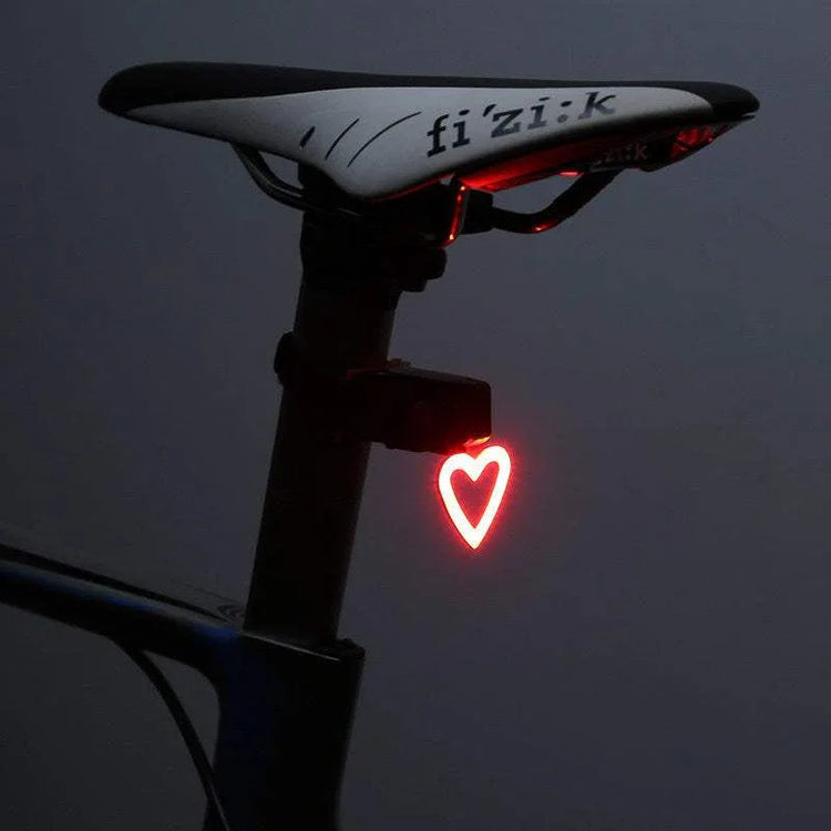 Black and white bike seat with glowing red heart-shaped LED tail light