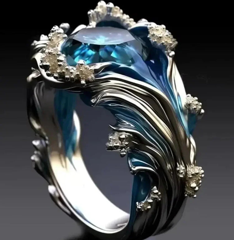 Silver and blue ring with wave-like design, blue gemstone, and crystal accents