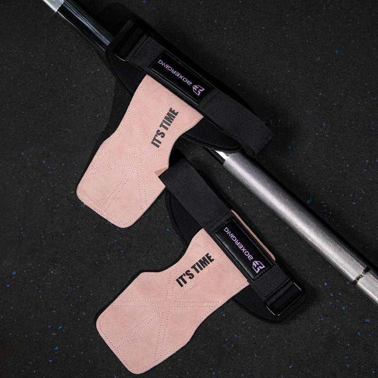 Pair of pink suede weightlifting straps with black elastic bands on a gym bar