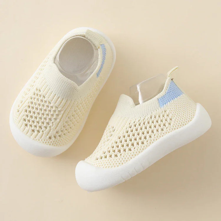 Cream knit baby shoes with white soles, breathable mesh design, slip-on fit, blue accent