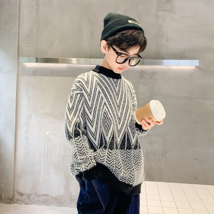 Kid in oversized black and white knit sweater, beanie, and glasses holding coffee cup indoors