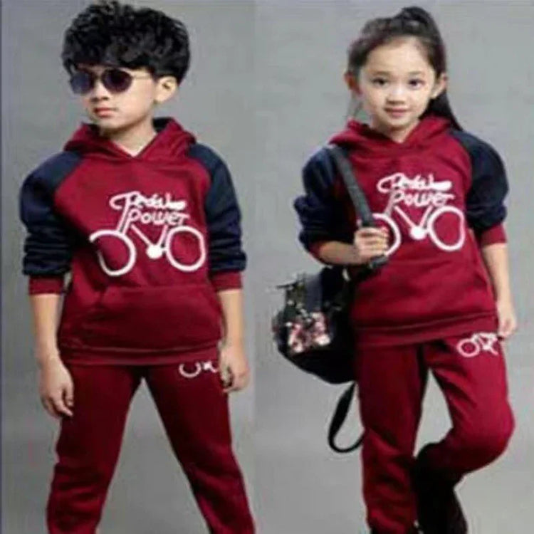 Kids in matching maroon and navy hoodie tracksuits with bicycle print, relaxed fit.