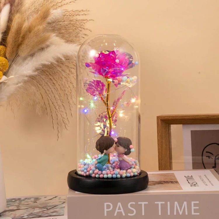 Glass dome with pink LED rose, fairy lights, and kissing couple figurines on pastel beads