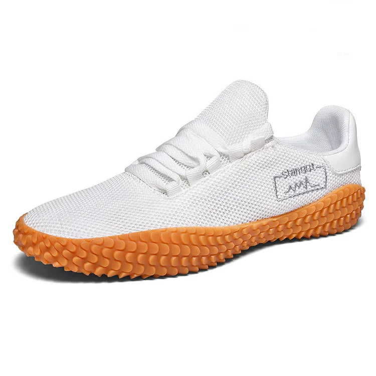 White mesh sneaker with orange textured sole and low-top fit, modern streetwear style.