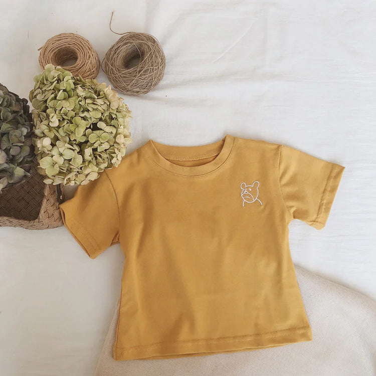 Yellow cotton short sleeve t-shirt with white bear embroidery, relaxed fit, laid flat