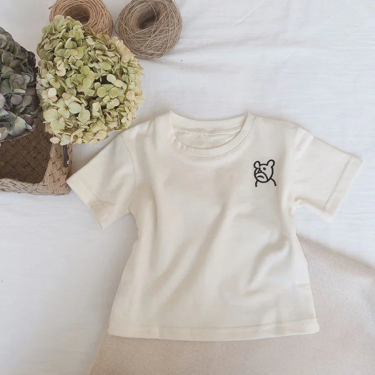 Beige short sleeve cotton t-shirt with small bear graphic, relaxed fit, flat lay style