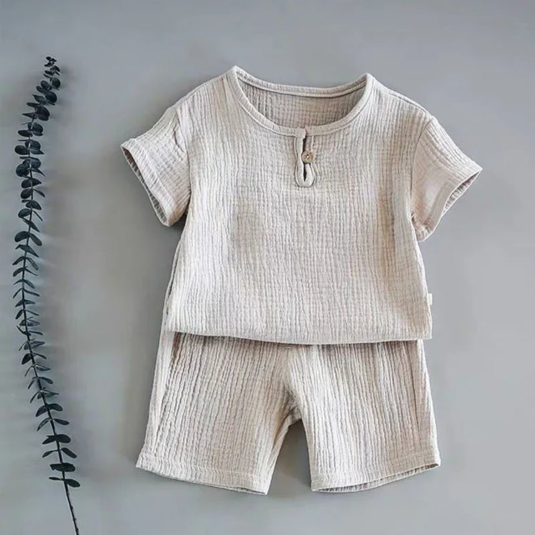 Beige short sleeve cotton set with textured fabric and relaxed fit, flat lay on grey background.