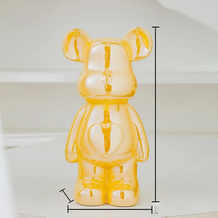 Shiny yellow bear figurine with heart detail, measuring height and width on white background.