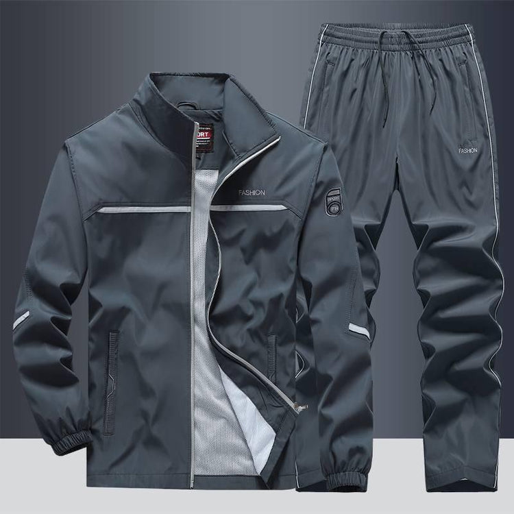 Dark grey streetwear tracksuit set with zip-up jacket and elastic waist pants, lightweight fabric, relaxed fit.