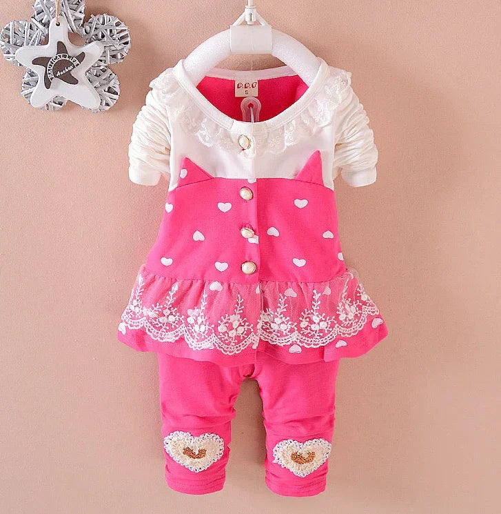 Pink and white baby outfit with heart prints, lace trim, and ruffled tulle skirt, long sleeves.