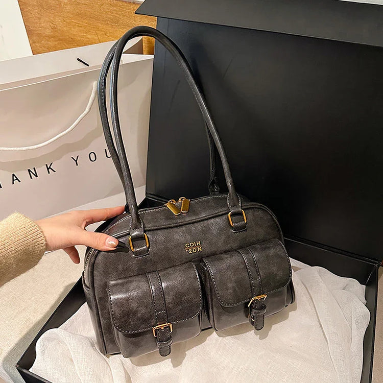 Black faux leather handbag with double front buckle pockets, gold hardware, and structured fit