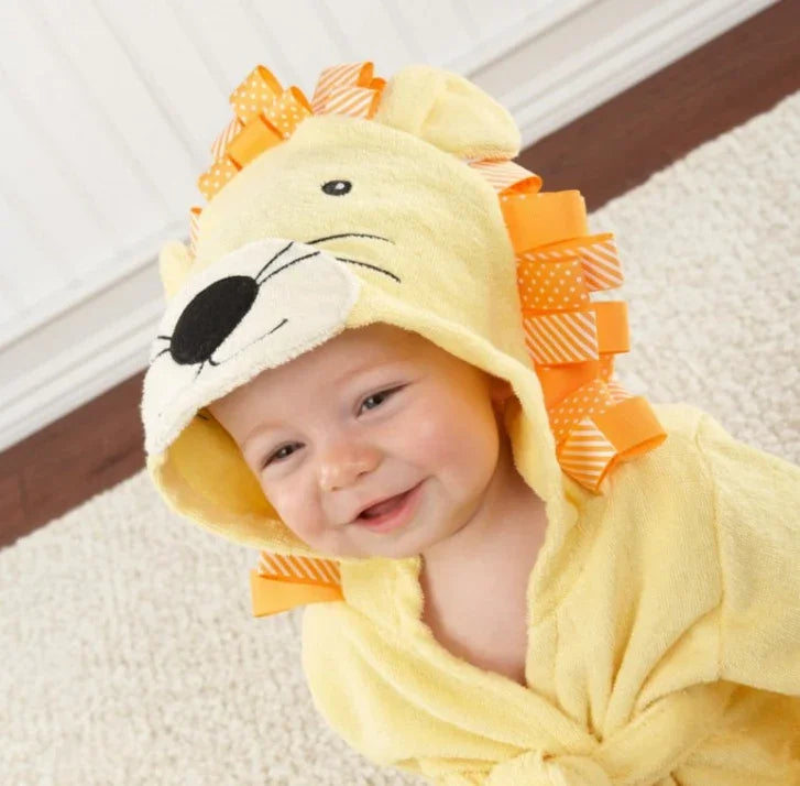 Smiling baby in a yellow lion-themed hooded towel with orange mane, cozy fit and soft fabric