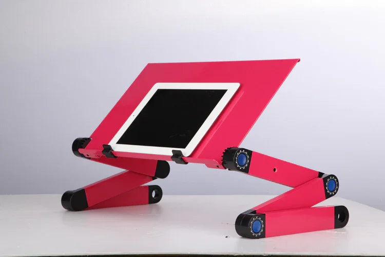 Adjustable pink metal laptop stand with folding legs and tablet holder on white desk