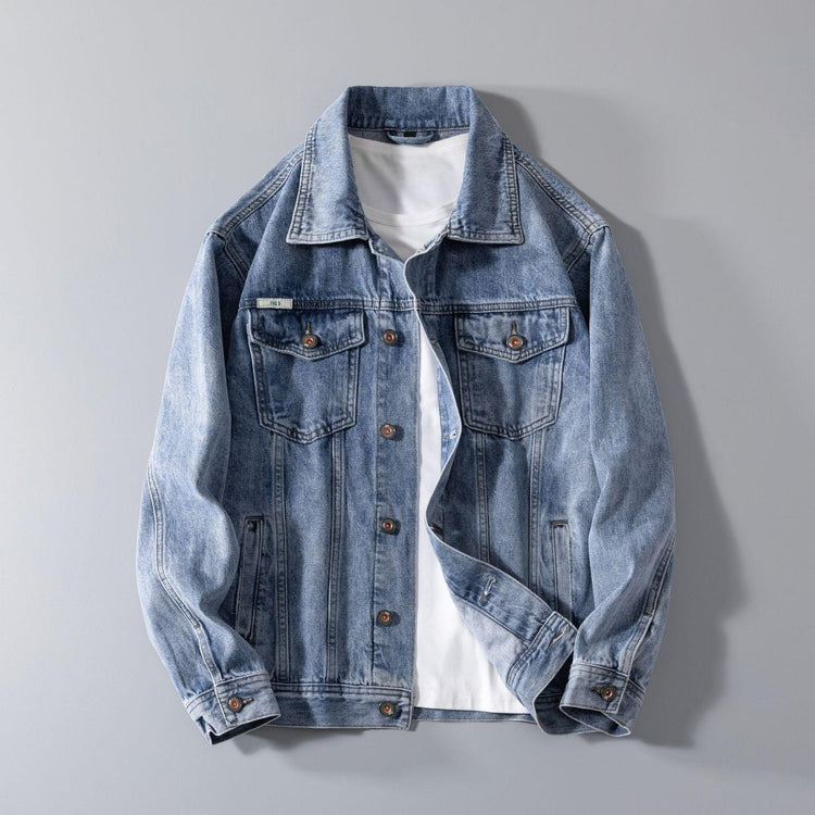 Light blue denim jacket with button front, classic collar, and relaxed fit layered over white shirt