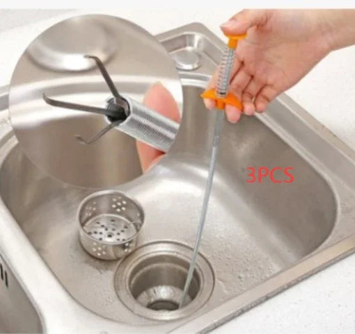 Flexible spring drain clog remover tool with orange handle used in kitchen sink, metal claws extended