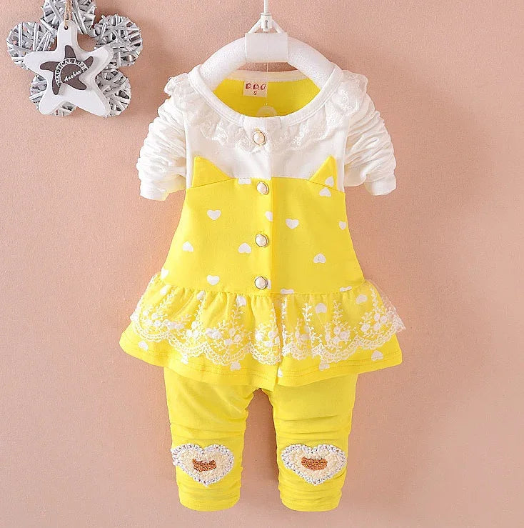 Yellow and white toddler outfit with heart patterns, lace trim, and fitted leggings