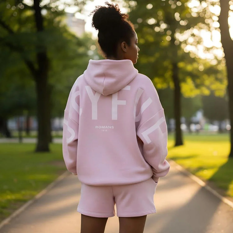 Woman wearing oversized pastel pink hoodie and matching shorts, casual streetwear style