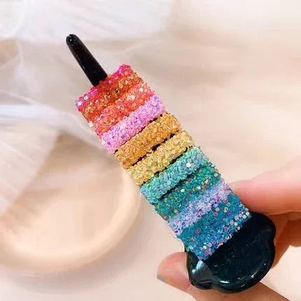 Hand holding a stack of multicolored glittery elastic hair ties, soft stretch material, vibrant colors