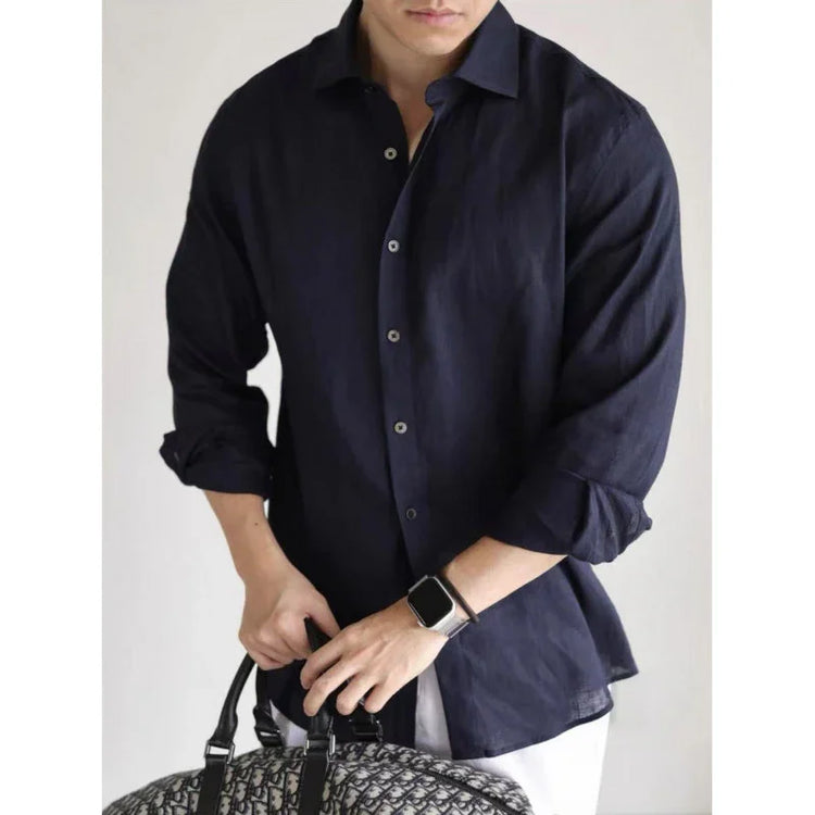 Man wearing a relaxed-fit navy linen button-up shirt with rolled sleeves, holding a patterned bag