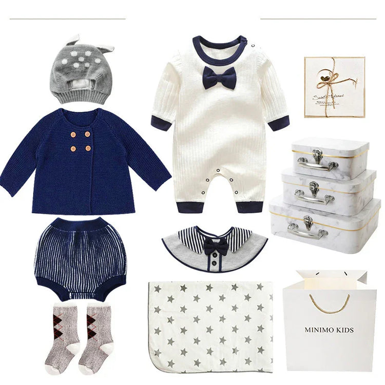 Baby clothing set with navy and white knit sweater, romper, shorts, socks, and star-patterned blanket.