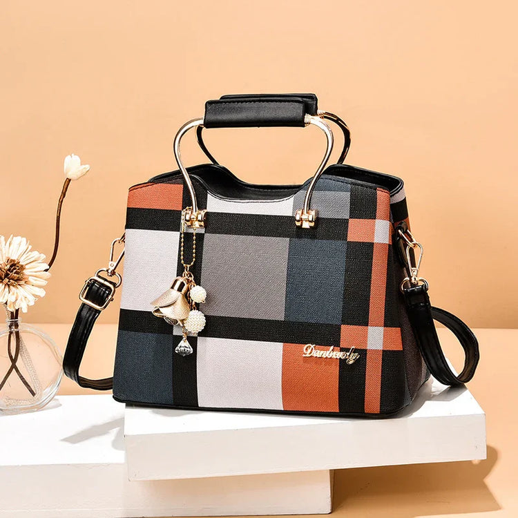 Plaid box-shaped handbag with black leather handle, gold hardware, and detachable strap