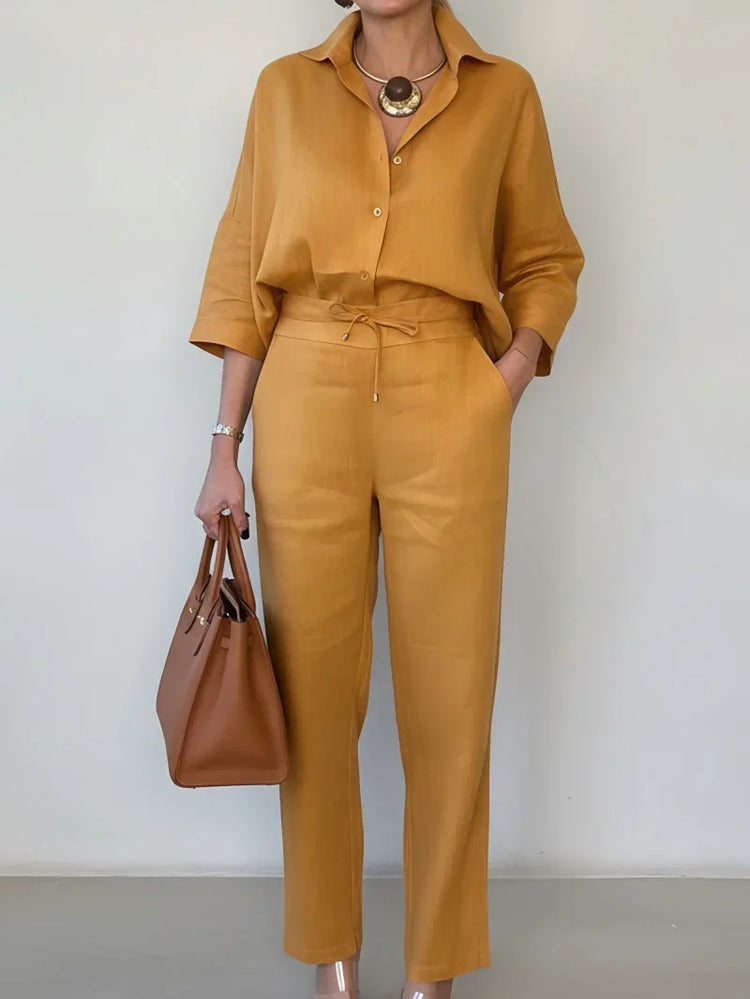 Woman in loose-fit mustard yellow button-up shirt and drawstring pants, holding brown tote bag