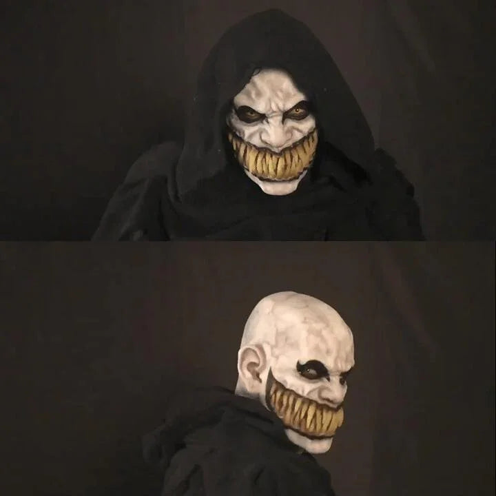 Person in black hooded cloak with scary yellow-toothed face mask, gothic streetwear style