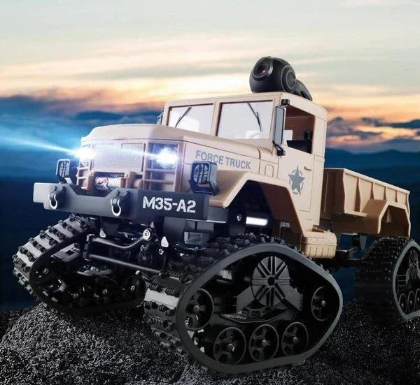 Beige military-style RC truck with rugged tank tracks and LED headlights on rocky terrain