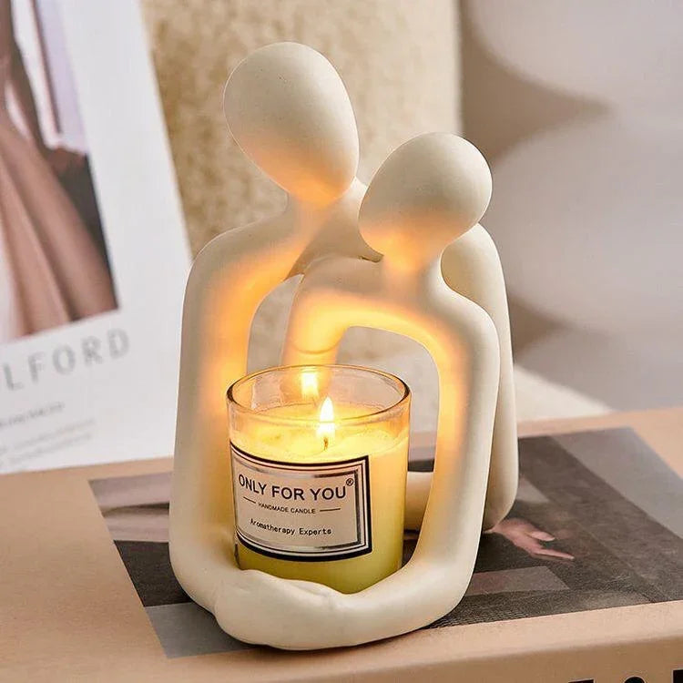 Minimalist cream ceramic sculpture holding a lit yellow candle in a glass holder