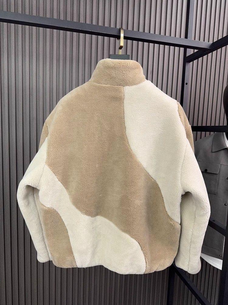 Beige and cream colorblock sherpa fleece jacket with relaxed fit and high collar, hanging on rack