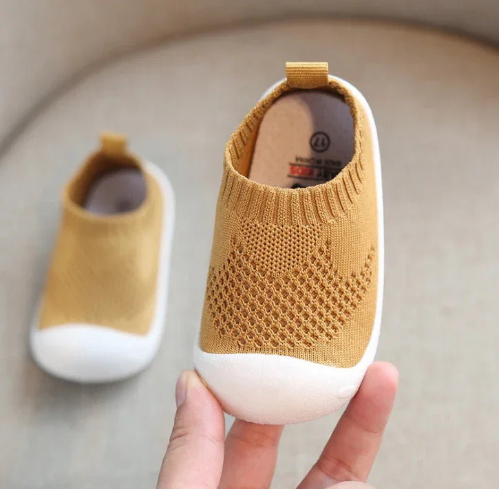 Knitted slip-on baby shoes in mustard yellow with breathable mesh and white rubber toe