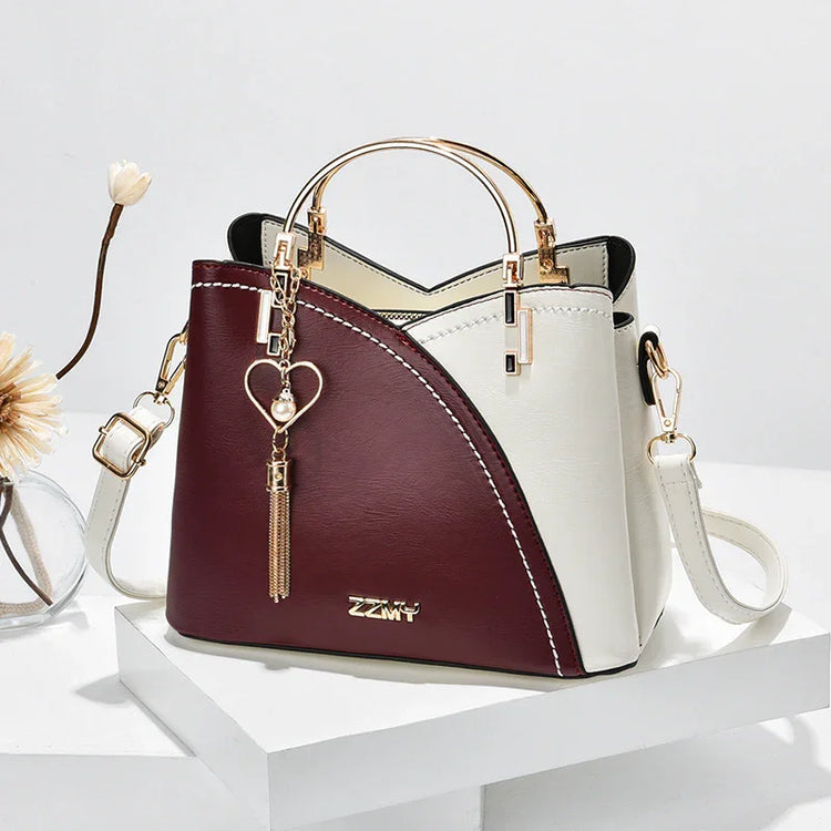 Elegant two-tone handbag in burgundy and cream faux leather with gold hardware, structured fit