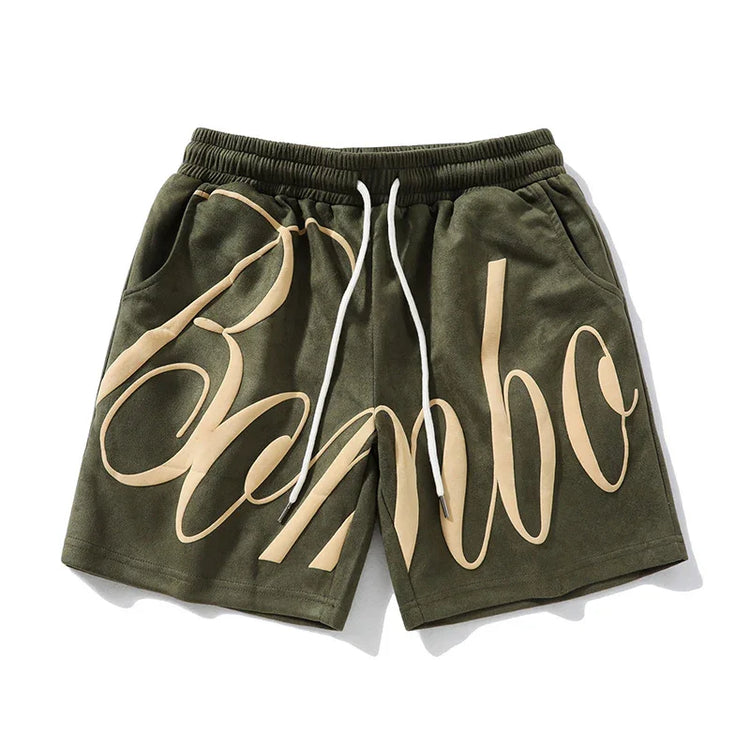 Olive green streetwear shorts with beige graphic text, drawstring waist, relaxed fit
