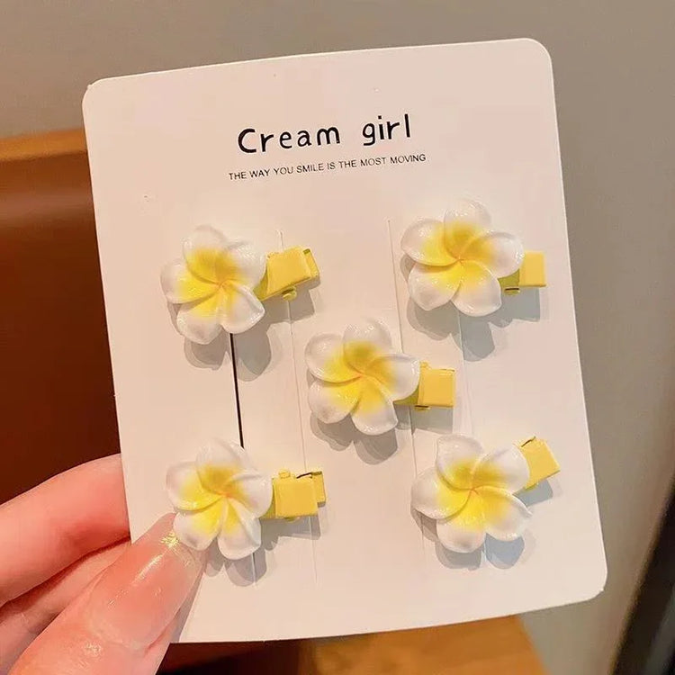 Set of six yellow and white plumeria flower hair clips on display card, floral accessory