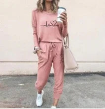 Woman in pink casual loungewear set with graphic top and jogger pants, holding coffee