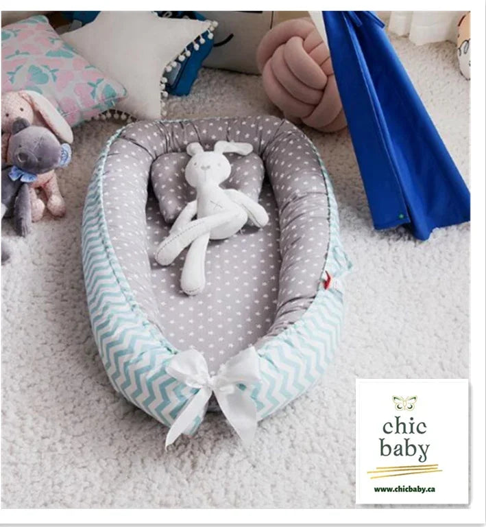 Soft grey and white polka dot baby nest with chevron border, plush dolls, and bow detail