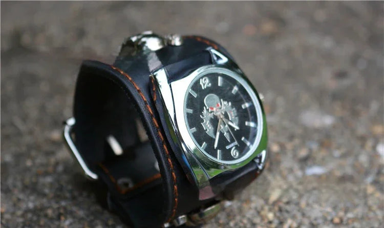 Black leather wide cuff watch with silver accents and a skeleton dial on a textured surface