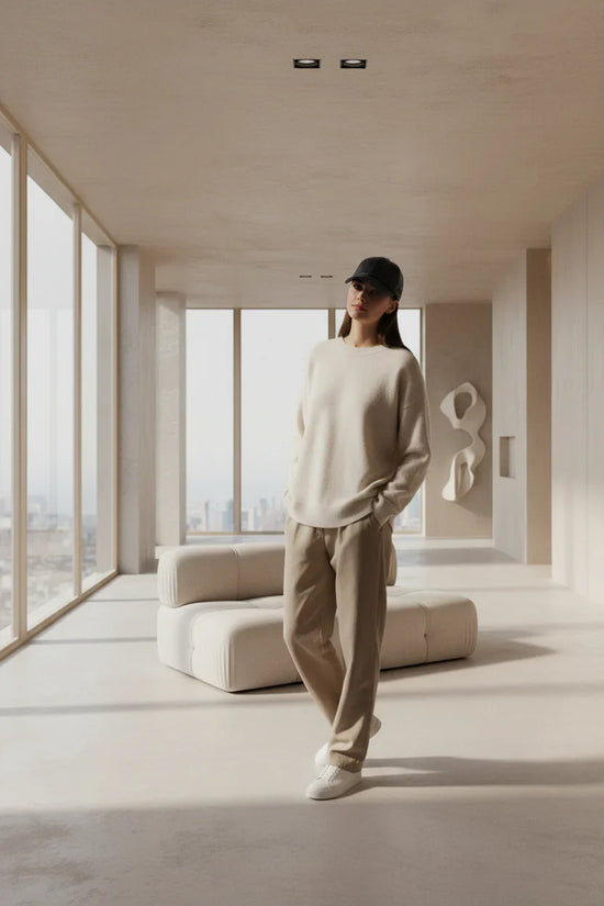 Woman in relaxed fit beige sweater and tan trousers, casual streetwear style, minimalist setting