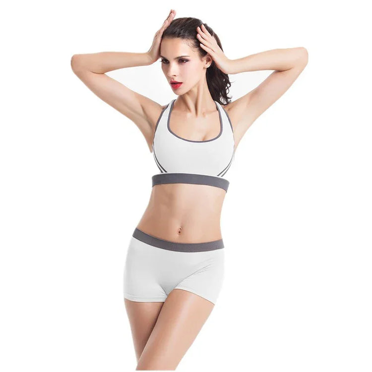 Woman wearing white athletic sports bra and shorts with gray trim, fitted and seamless style