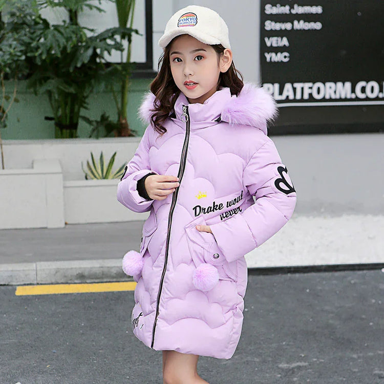 Girl wearing a light purple puffer coat with faux fur hood, heart sleeve detail, and pom-poms