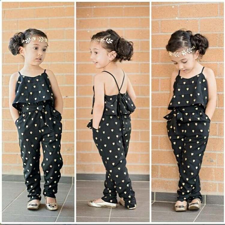 Girl wearing black heart print jumpsuit with ruffle top and adjustable straps, relaxed fit