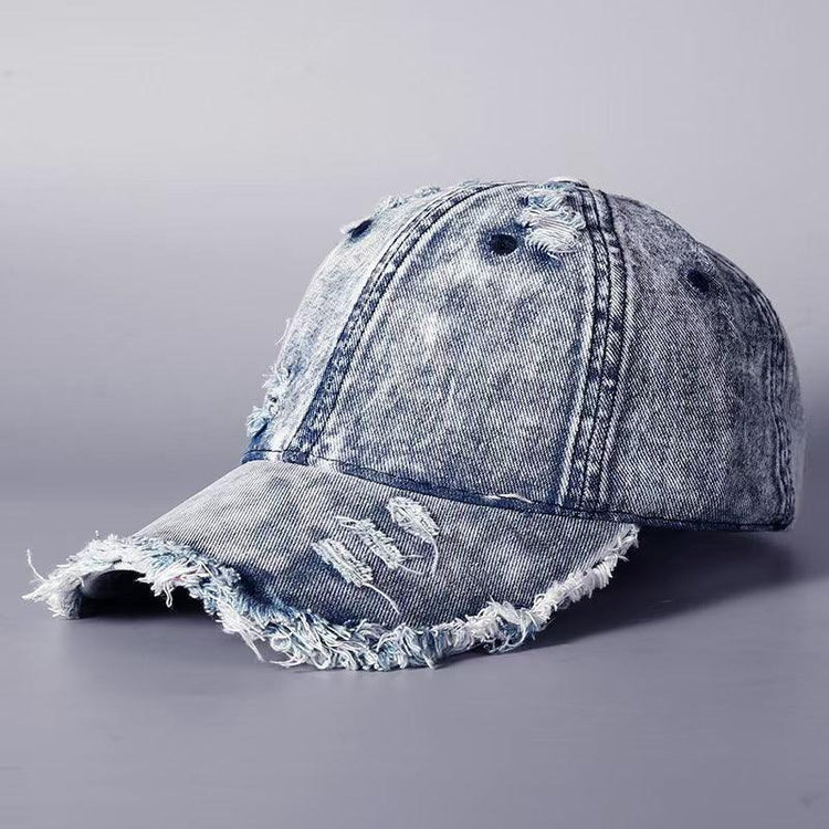 Distressed blue denim baseball cap with frayed edges and ripped details, casual streetwear style