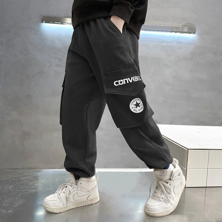 Black cargo pants with oversized pockets and graphic patches, relaxed streetwear fit