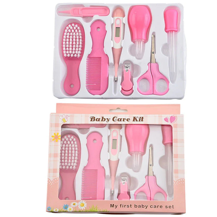 Pink baby grooming kit with brush, comb, thermometer, scissors, nail clipper, and dropper in plastic case.