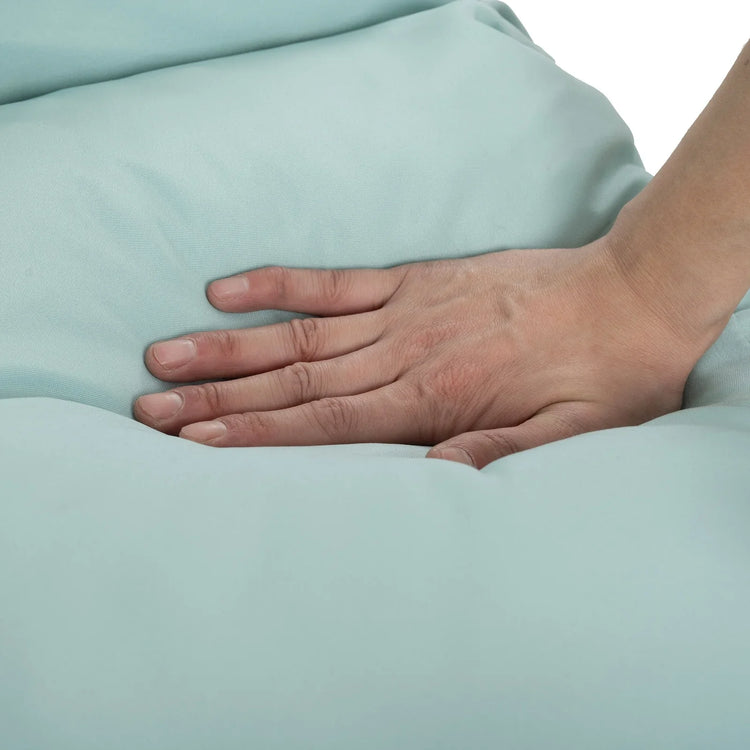 Hand pressing down on light blue padded fabric, showing soft, plush material texture