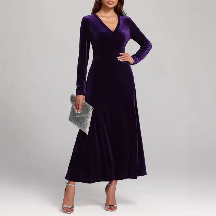 Woman wearing a long-sleeve, deep purple velvet maxi dress with a V-neck and fitted waist